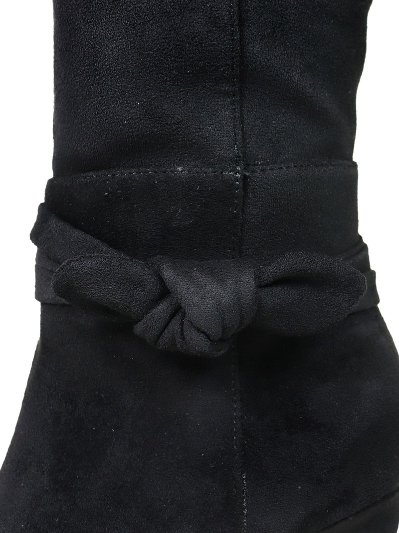 Close-up of the Frederick's of Hollywood Janeth Ankle Heel Boots in black suede, showcasing a decorative knot detail on the shaft and set atop a chic chunky heel.