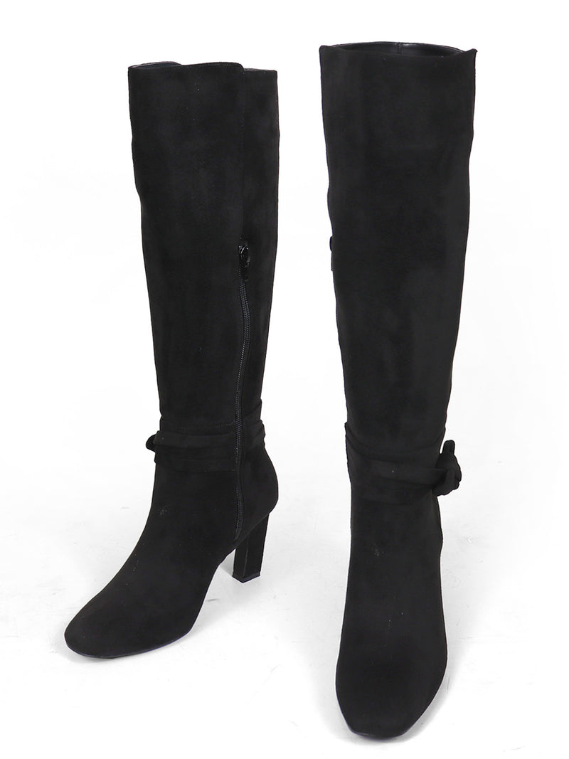 Introducing the Janeth Ankle Heel Boots by Frederick's of Hollywood: These chic black suede boots feature knee-high coverage, side zippers, and decorative straps with a subtle knot detail around the ankles. Set on a stylish chunky heel, they blend classic elegance with modern accents for a sophisticated look. Shown on a white background.