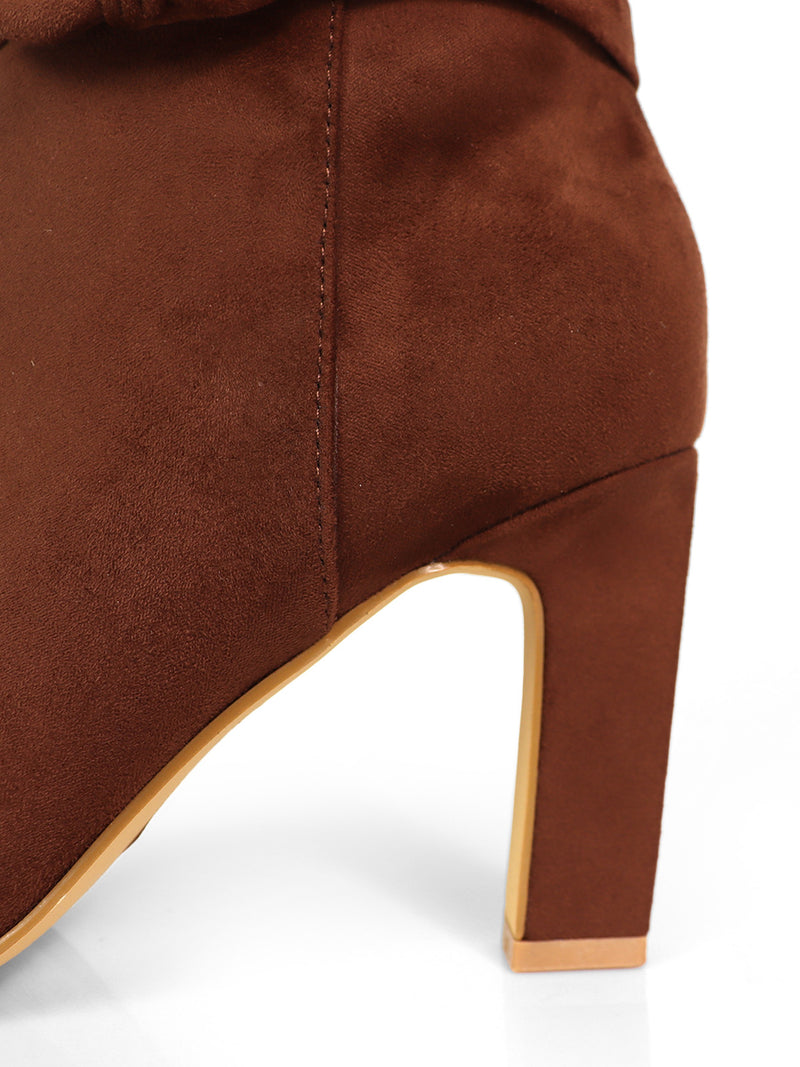 Close-up of the Janeth Ankle Heel Boots by Frederick's of Hollywood, featuring brown suede with a chunky heel, detailed stitching, and a light tan sole, set against a white background.