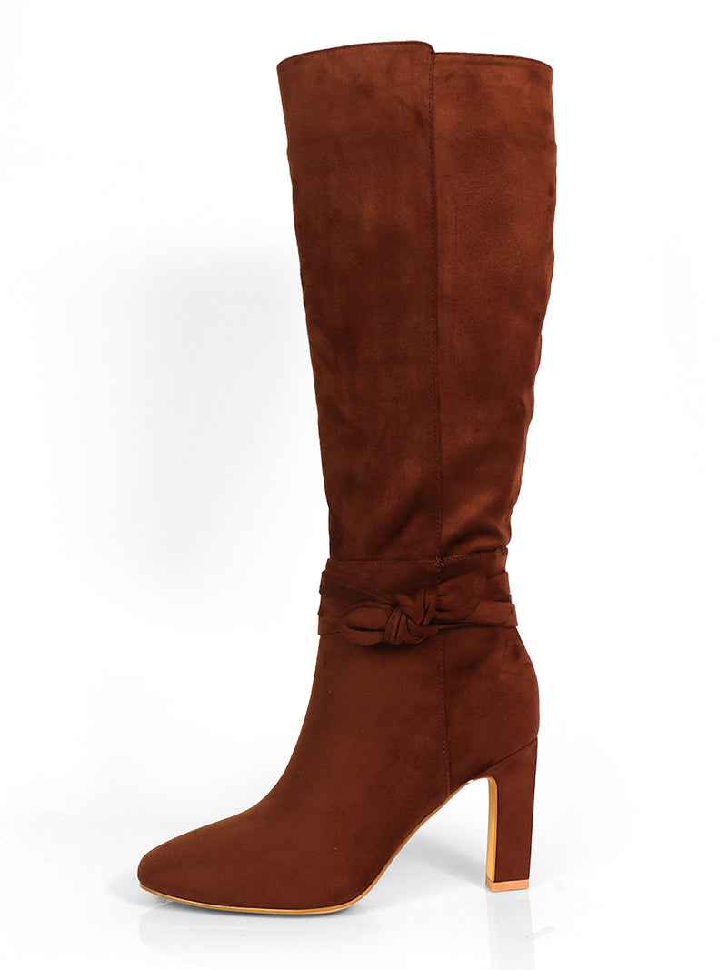 The Janeth Ankle Heel Boots by Frederick's of Hollywood are chic tall brown suede boots featuring a high block, chunky heel, rounded toe, and a decorative knot-detail strap around the ankle—beautifully displayed on a white background.