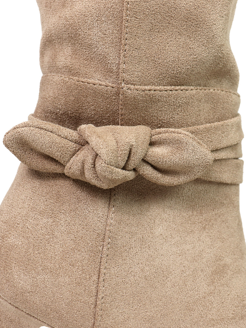 Close-up of the Janeth Ankle Heel Boots by Frederick's of Hollywood in tan suede, showcasing a decorative suede strap with knot detail wrapped around the ankle, which highlights the soft texture and meticulous stitching of the material.