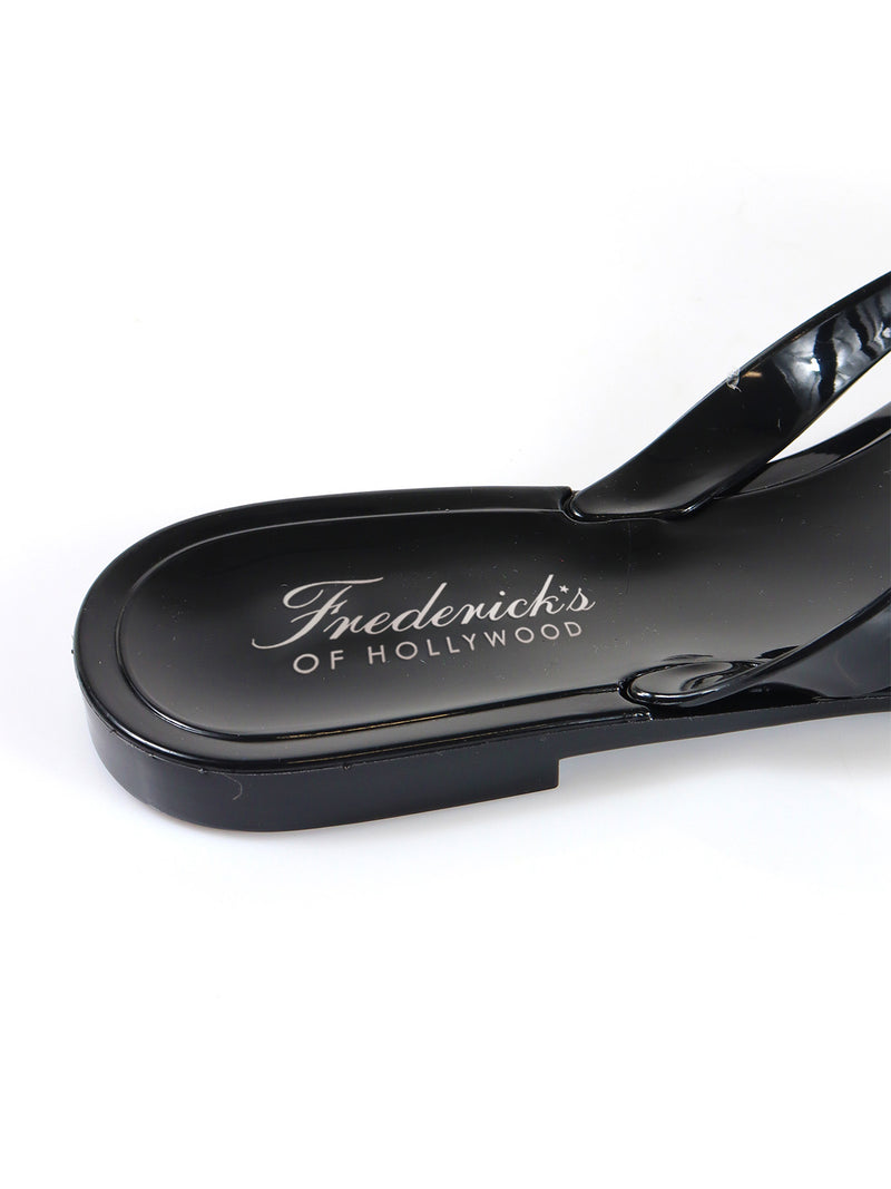 A close-up of the black, glossy Jelli Camellia Thong Sandals by Frederick's of Hollywood, featuring the brand‚Äôs white script on the insole. Shown against a white background, these sandals add chic style to your warm-weather wardrobe.