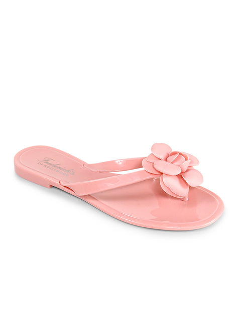 The Frederick's of Hollywood Jelli Camellia Thong Sandals feature a light pink glossy finish, camellia-inspired strap detailing, a flat sole, and an open-toe design.