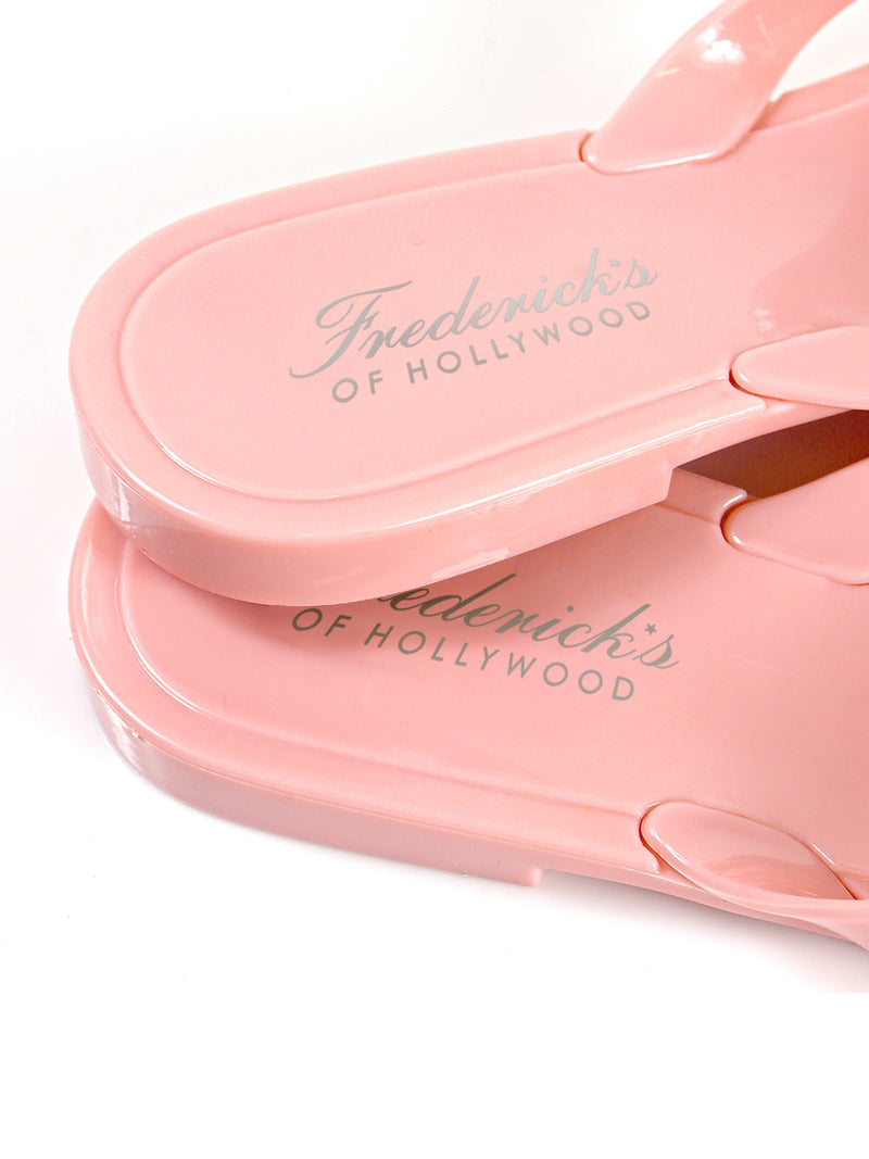 Close-up of two pink Jelli Camellia Thong Sandals by Frederick's of Hollywood, stacked on a white background. Footbeds feature the brand name in silver and camellia-inspired details add a chic touch.
