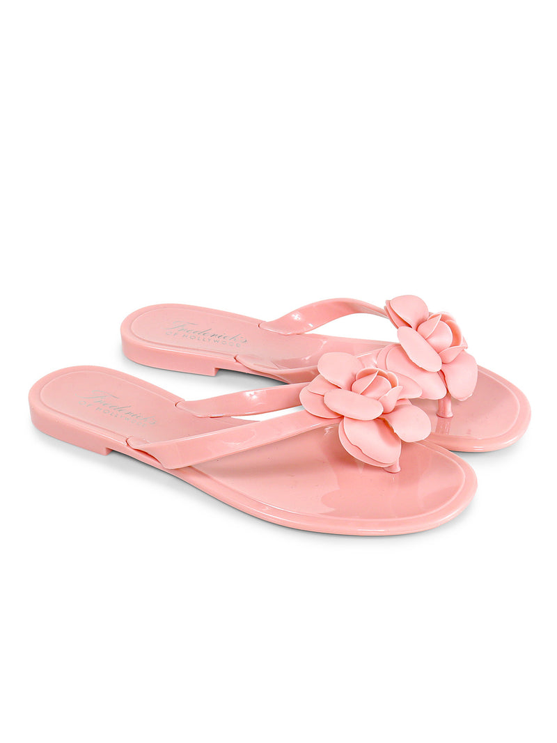 A pair of glossy light pink Jelli Camellia Thong Sandals from Frederick's of Hollywood, featuring camellia-inspired details and large pink flower decorations on top.