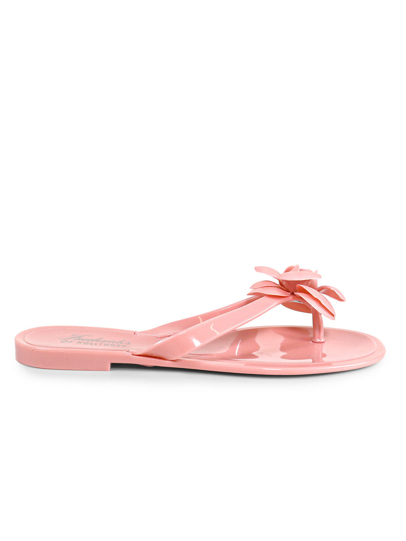 A glossy, light pink Jelli Camellia Thong Sandal by Frederick's of Hollywood features camellia-inspired details and a decorative flower on the strap, shown in a side view against a white background.