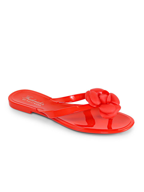 The Jelli Camellia Thong Sandals by Frederick's of Hollywood feature a bright red glossy finish, flat sole, thong strap, and a bold camellia-inspired flower detail on top.