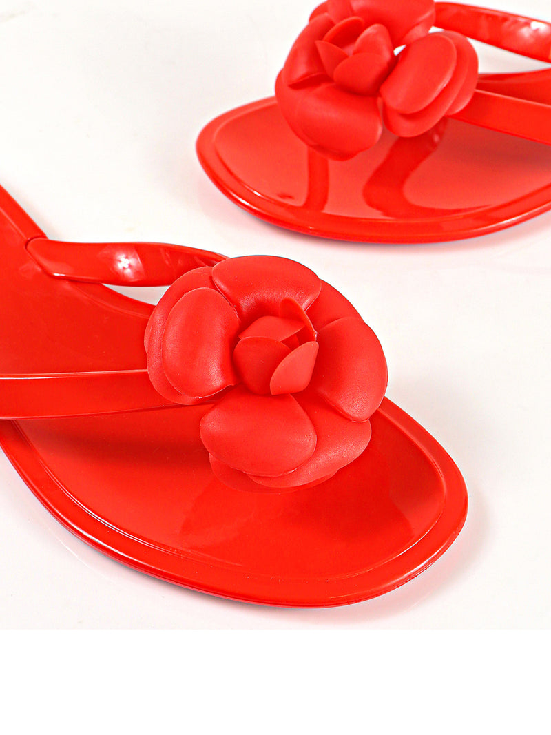 Close-up of Frederick's of Hollywood Jelli Camellia Thong Sandals in bright red, featuring camellia-inspired strap detailing, displayed on a white background.