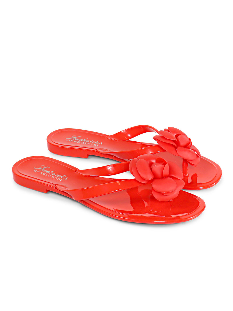 Jelli Camellia Thong Sandals by Frederick's of Hollywood feature shiny red straps with large decorative camellia flowers, offering a stylish footwear choice for warm weather, shown against a white background.