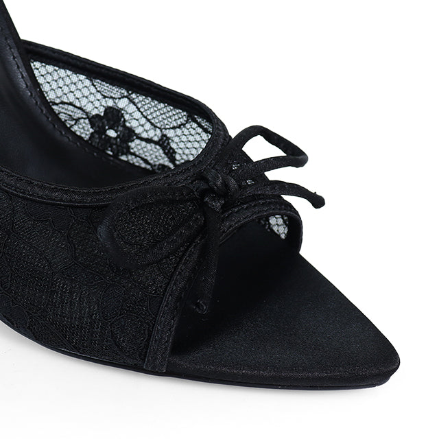 Close-up of Frederick's of Hollywood Lacey Pointed Toe Lace Bow Heels: black heels with lace detailing, a chic front bow, and inner lining featuring a delicate floral lace pattern for a sophisticated finish.