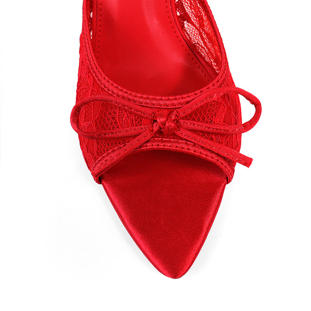 A close-up top view of Frederick's of Hollywood Lacey Pointed Toe Lace Bow Heels showcases intricate lace detail and an elegant front bow, set against a white background.