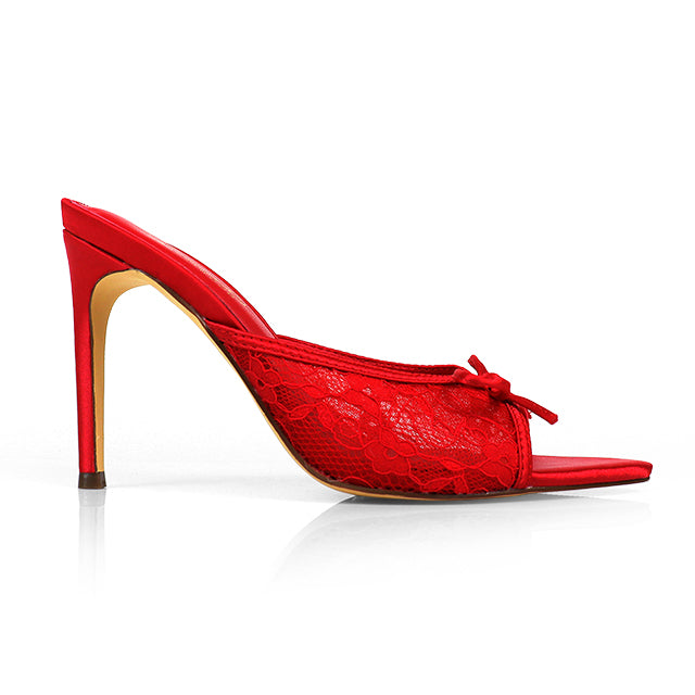 The Lacey Pointed Toe Lace Bow Heels by Frederick's of Hollywood feature red lace, a high heel, open toe, and elegant bow, displayed in profile against a white background.