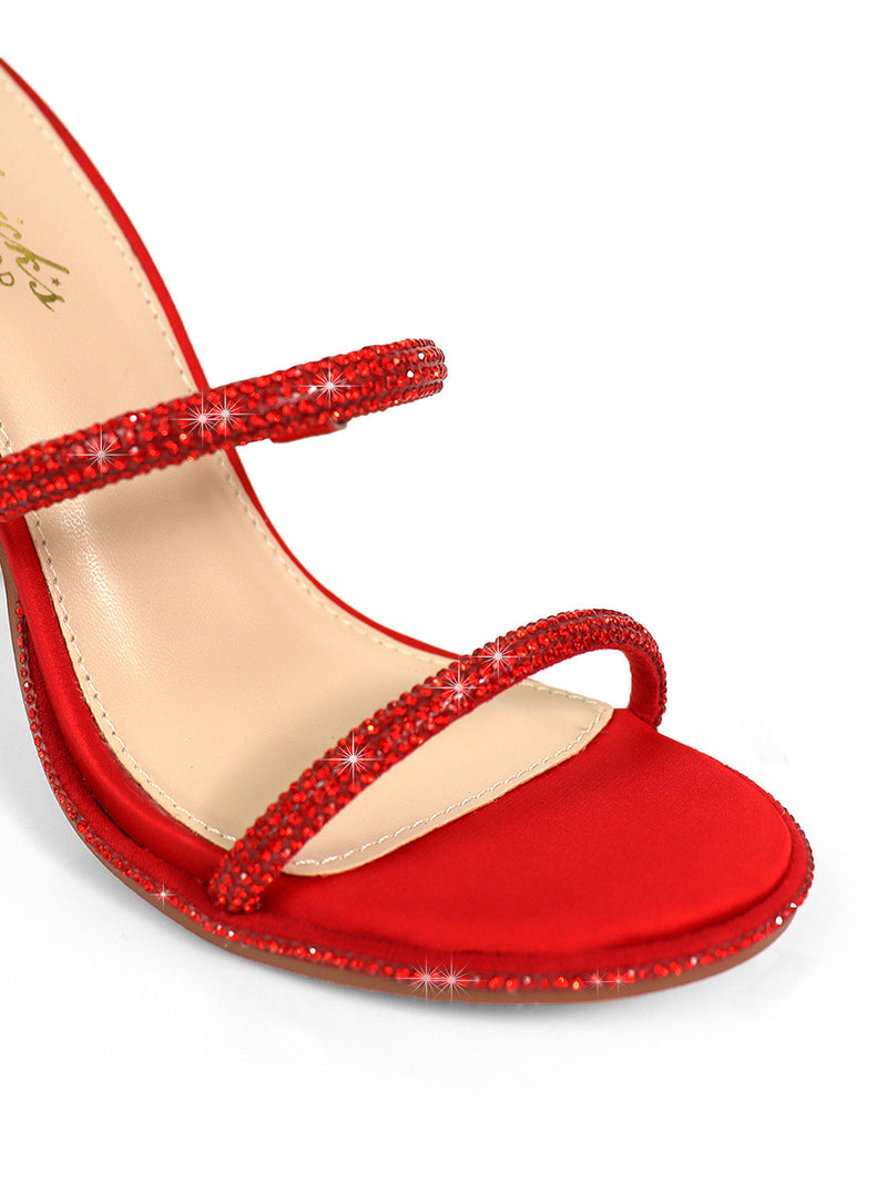 Close-up of the Lexia Rhinestone Heel by Frederick's of Hollywood—a red open-toe stiletto with two thin, rhinestone-encrusted straps over a beige insole. These sparkling heels radiate elegance and luxury.