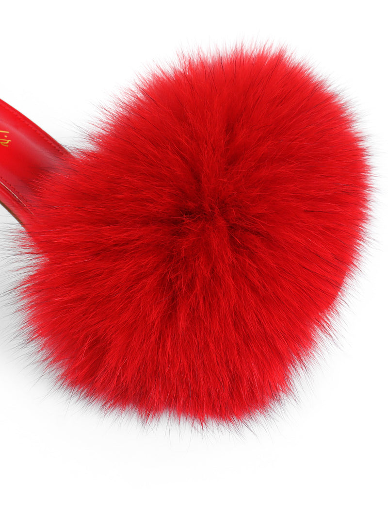 A close-up of the Purr Square Toe Fur Heel by Frederick’s of Hollywood showcases a chic red slipper with a square-toe silhouette and plush, voluminous faux fur on top, highlighted by a visible red sole, all set against a white background.