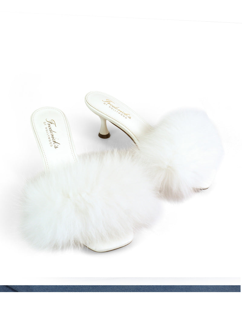 Introducing the Purr Square Toe Fur Heel by Frederick’s of Hollywood: a pair of white high-heeled mules featuring fluffy faux fur upper straps and a chic square-toe silhouette, showcased against a plain white background.