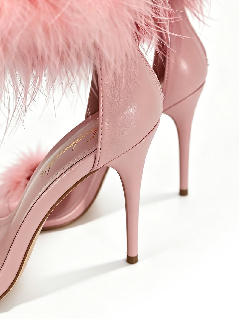 Close-up of two Raquel Feather Stiletto Heels by Frederick’s of Hollywood, showcasing elegant feather detailing along the trim. Set against a white background, these shoes feature pointed toes and glossy stiletto heels, delivering a feminine and sophisticated statement design.
