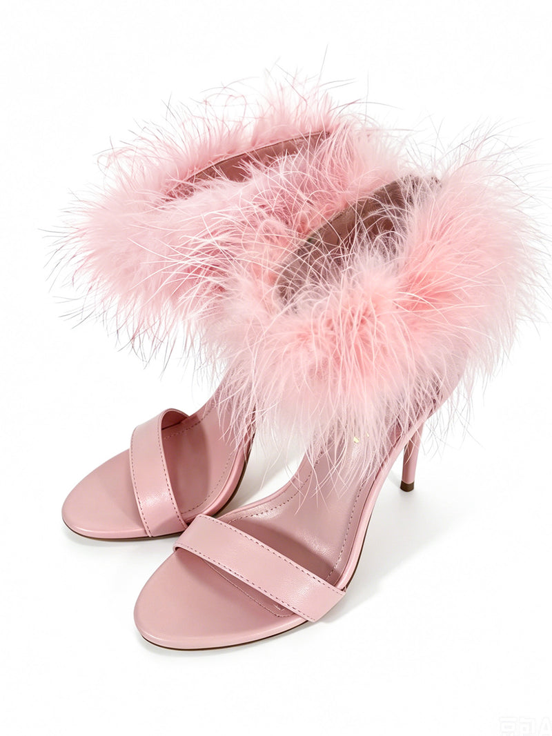 The Raquel Feather Stiletto Heel by Frederick’s of Hollywood features elegant feather detailing around the ankle straps, with a pink high-heeled sandal design set against a white background for a true statement look.