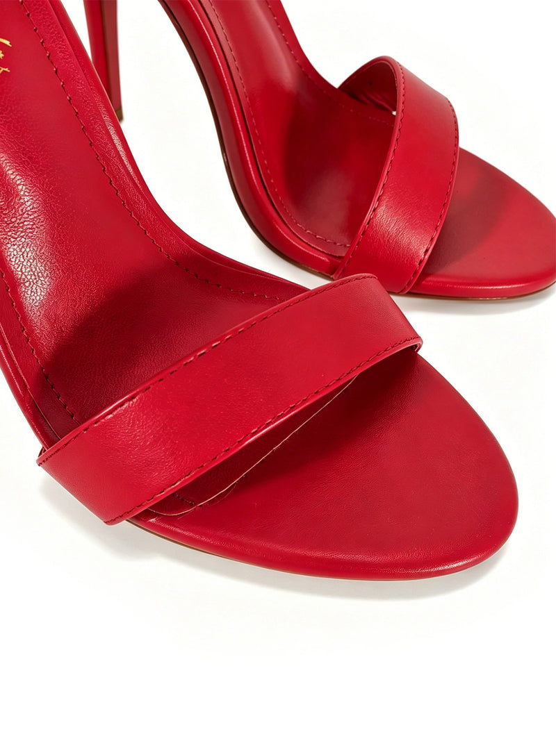 Close-up of the Raquel Feather Stiletto Heel by Frederick’s of Hollywood—a pair of red high-heeled sandals featuring a single strap across the toes and an open-toe design, set against a white background for a modern, luxurious silhouette.