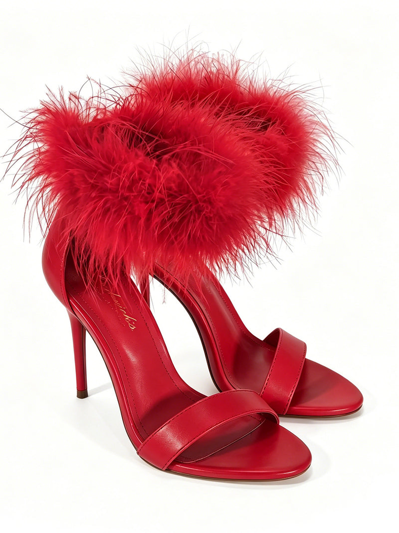 The Raquel Feather Stiletto Heel by Frederick’s of Hollywood features vibrant red high-heeled sandals with open toes and soft red feather trim along the ankle straps, elegantly displayed against a white background.