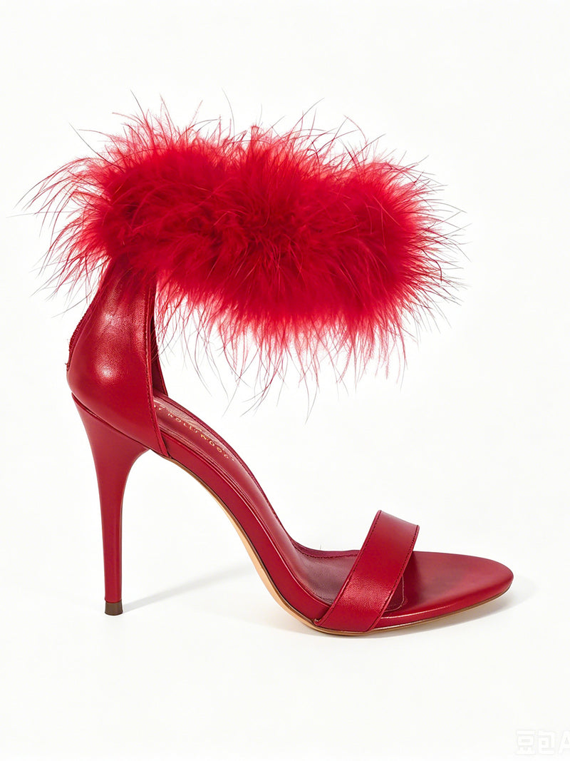 Introducing the Raquel Feather Stiletto Heel by Frederick’s of Hollywood—a striking red high-heeled sandal featuring a slim ankle strap embellished with plush red feathers and a minimalist front strap. This elegant design epitomizes modern luxury, beautifully showcased against a white background.