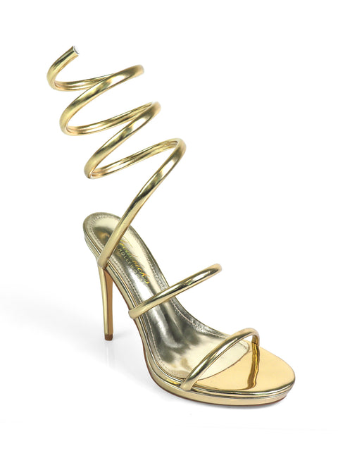 The Sabine Round Toe Heel by Frederick's of Hollywood features a shiny gold finish, three thin straps, and an exaggerated spiral ankle strap that coils upward for a bold look. Displayed on a plain white background.