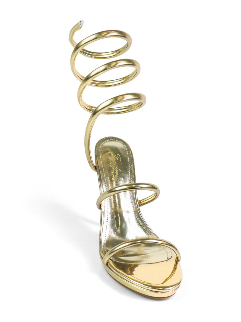 The Sabine Round Toe Heel by Frederick's of Hollywood is a gold high-heeled sandal with a distinctive spiral ankle strap, offering an elegant, modern look with its timeless silhouette.