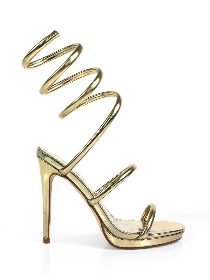 The Sabine Round Toe Heel by Frederick's of Hollywood is a gold high-heeled sandal featuring multiple spiral straps wrapping from the toe to above the ankle, shown against a plain white background.
