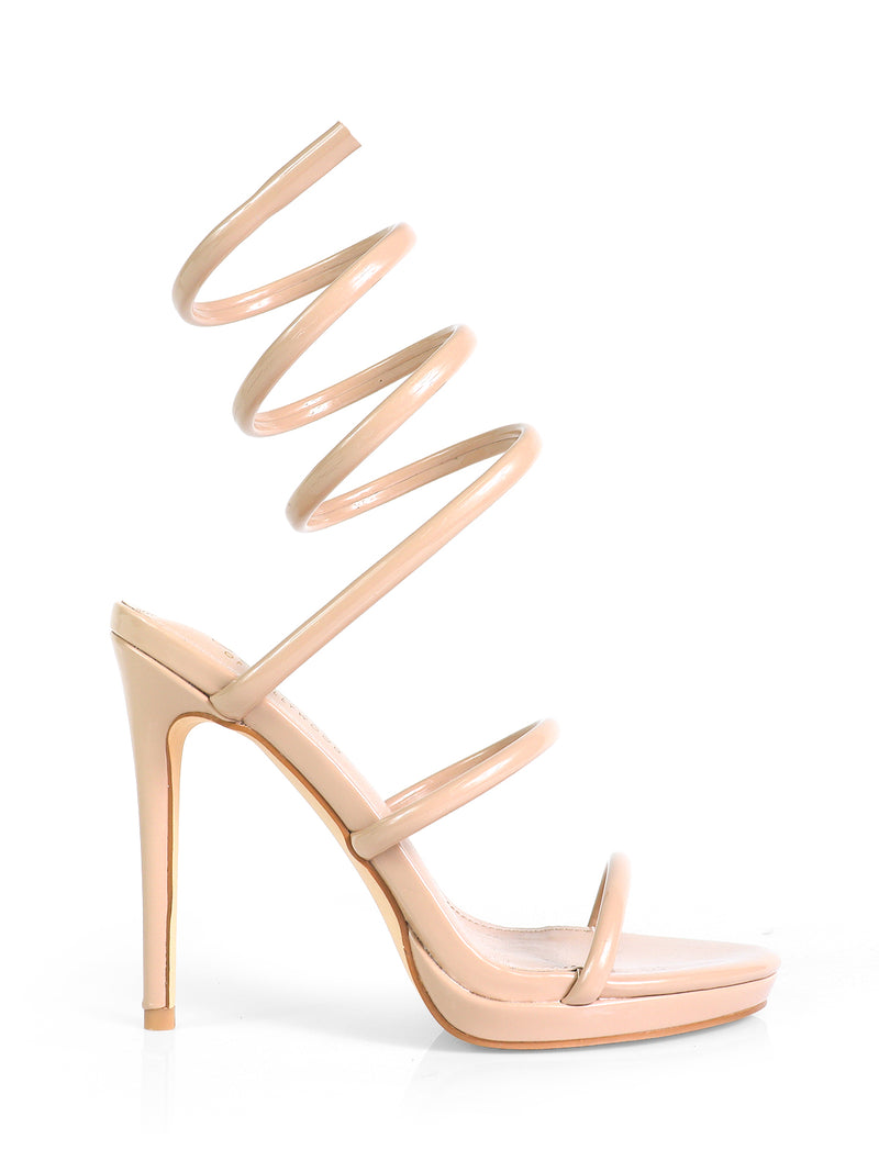 The Sabine Round Toe Heel by Frederick’s of Hollywood features a nude finish, three thin foot straps, and a spiral ankle strap wrapping up the leg. Photographed on a plain white background to showcase its versatile elegance.