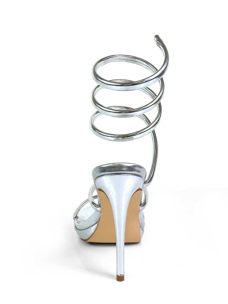 The Sabine Round Toe Heel by Frederick's of Hollywood features a shiny silver stiletto heel and spiral ankle strap, displayed from the back against a white background.