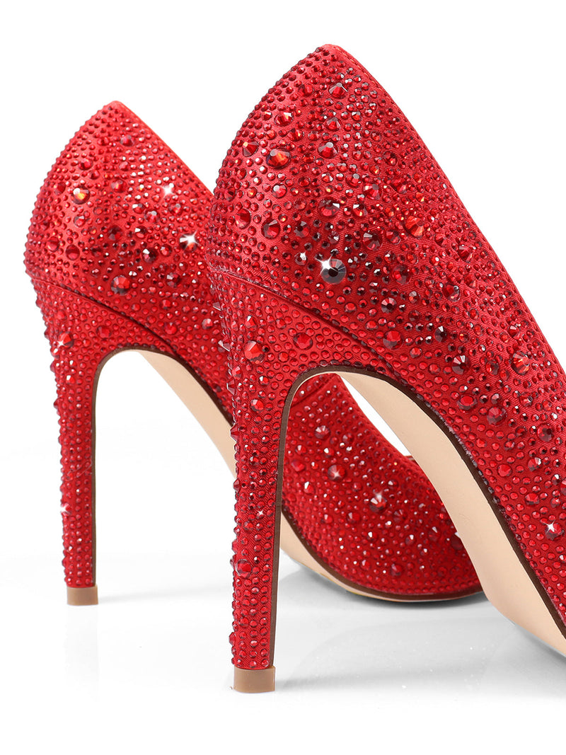 Close-up of two Samantha Pumps by Frederick's of Hollywood, featuring sparkling red rhinestones, beige soles, and high stiletto heels, set against a white background.