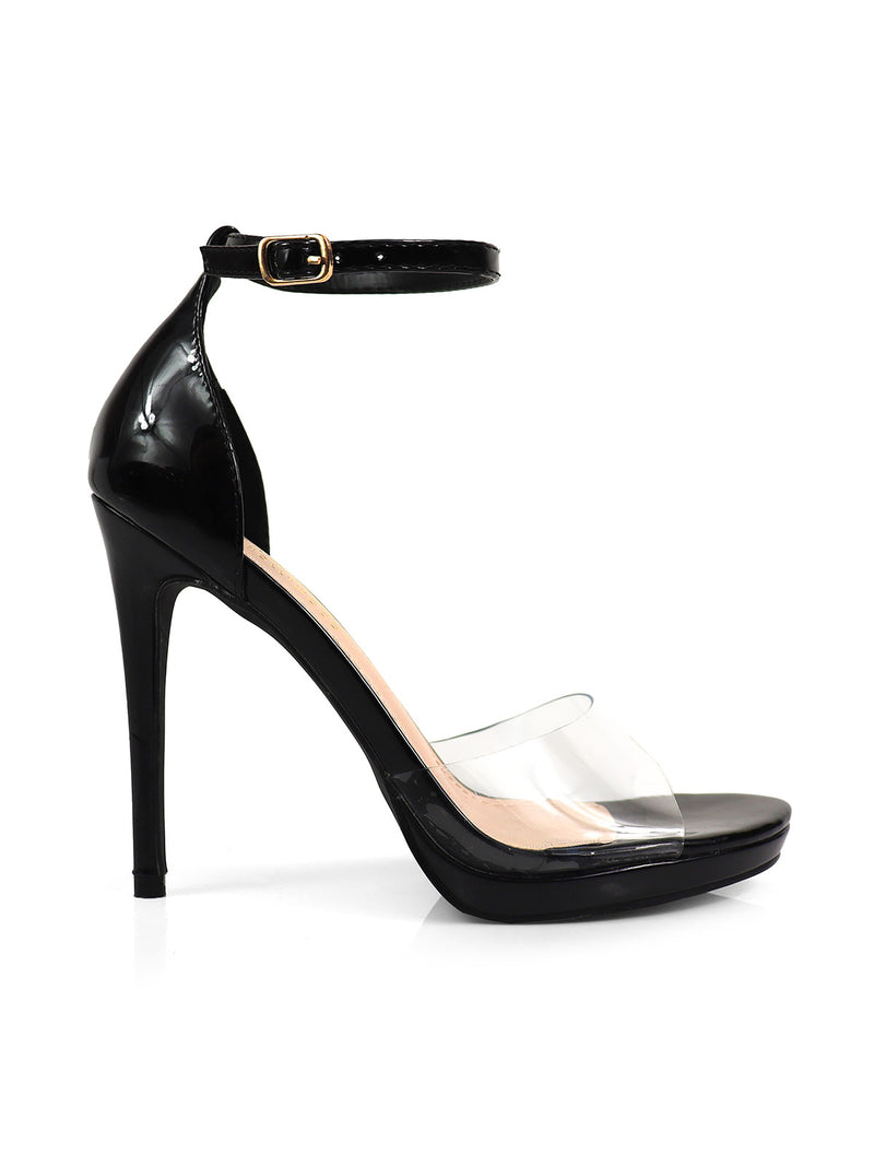 The Stacy Ankle Strap Heels by Frederick's of Hollywood feature a glossy black finish, gold buckle, and clear toe band, elegantly displayed against a white background.