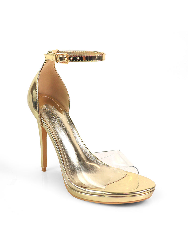 The Stacy Ankle Strap Heels by Frederick's of Hollywood feature a shiny gold finish, high heel, ankle strap, open toe, and clear front band, elegantly displayed against a plain white background.