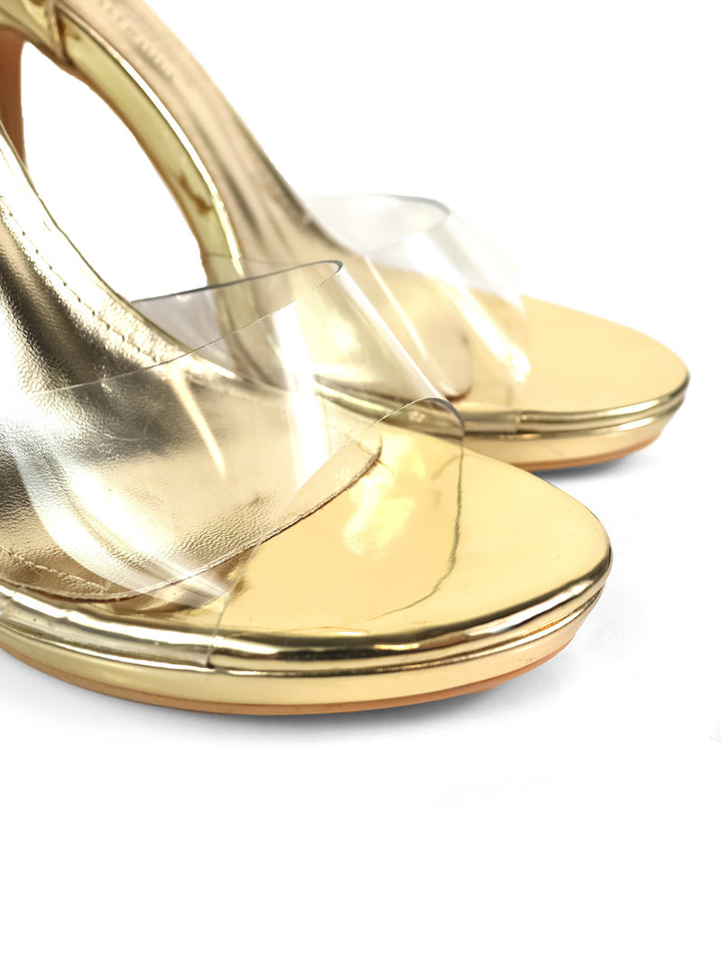 Close-up of Stacy Ankle Strap Heels by Frederick's of Hollywood—gold high-heeled sandals with clear straps, shown on a white background; versatile and perfect for any occasion.