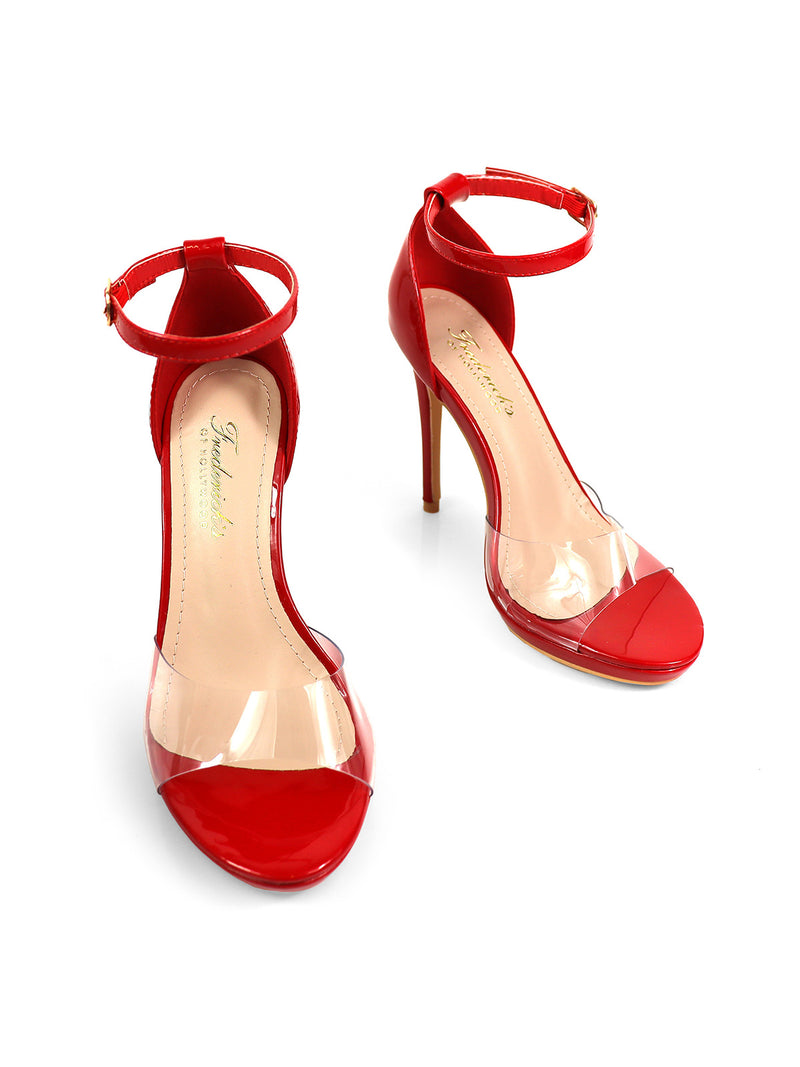 The Stacy Heel by Frederick's of Hollywood is a pair of red high-heeled sandals with ankle straps and clear PVC panels across the toes, shown on a white background.
