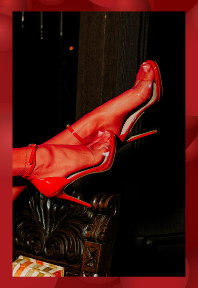 Model posing in red shoes on black background