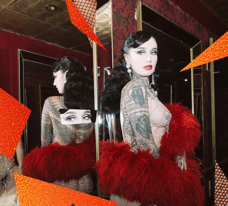 Woman in a red feathered outfit with tattoos standing in a mirror.