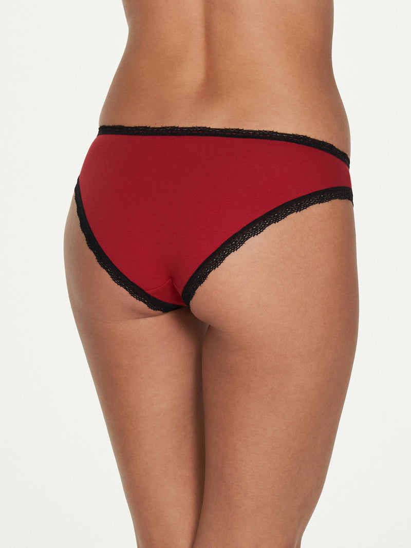 Someone models the Cora Cotton & Lace Hipster by Frederick's of Hollywood, featuring red lace with black trim, shown from the back against a plain background.