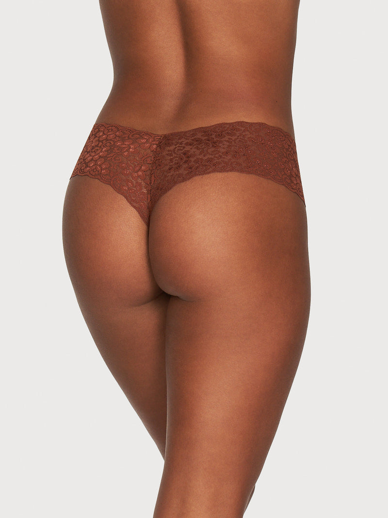 A person is seen from behind wearing Frederick's of Hollywood Emma Cotton & Lace Tanga, highlighting the intricate lace design and fit against the skin. The background is plain and light-colored.