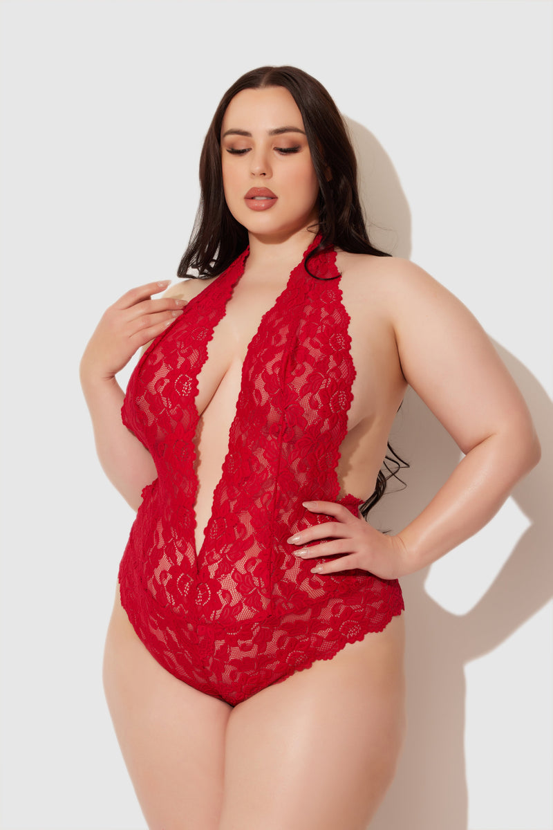 A woman with long dark hair poses confidently against a plain light background wearing the Jessica Lace Teddy by Frederick's of Hollywood.