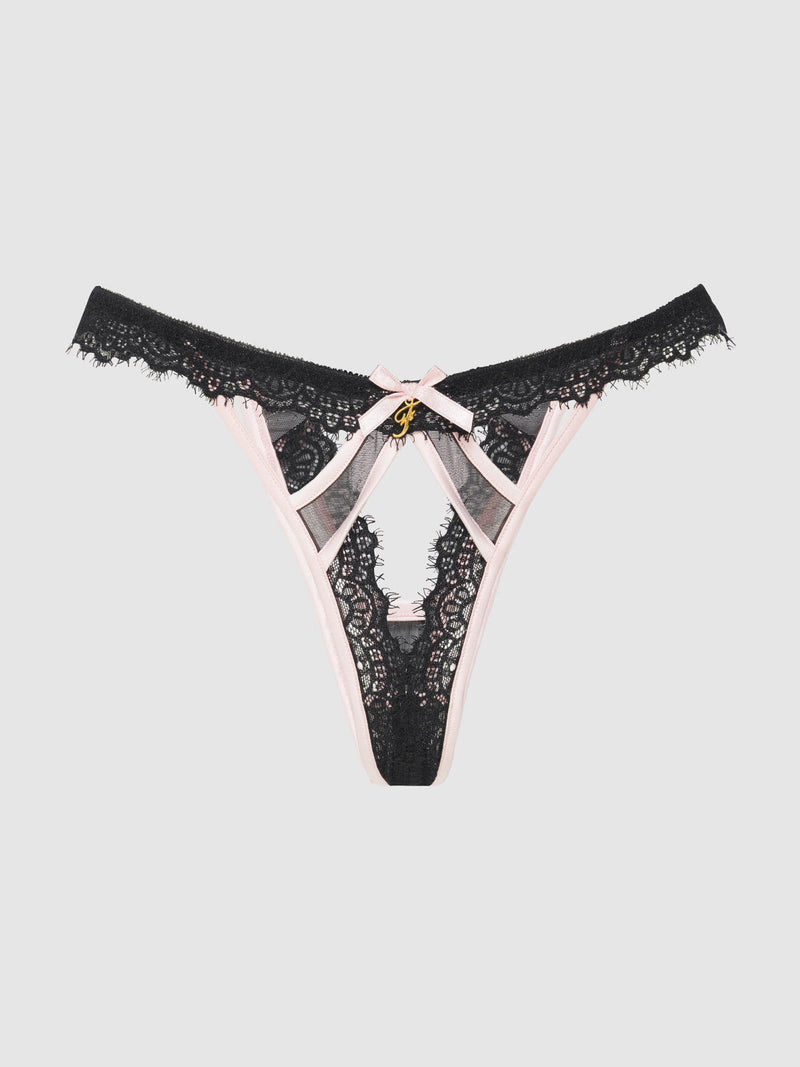 The Rosalind Satin & Lace Trim High-Waist Tanga by Frederick's of Hollywood features black lace, pink trim, crisscross straps, cutout details, and a gold charm at the front, shown on a plain light gray background.
