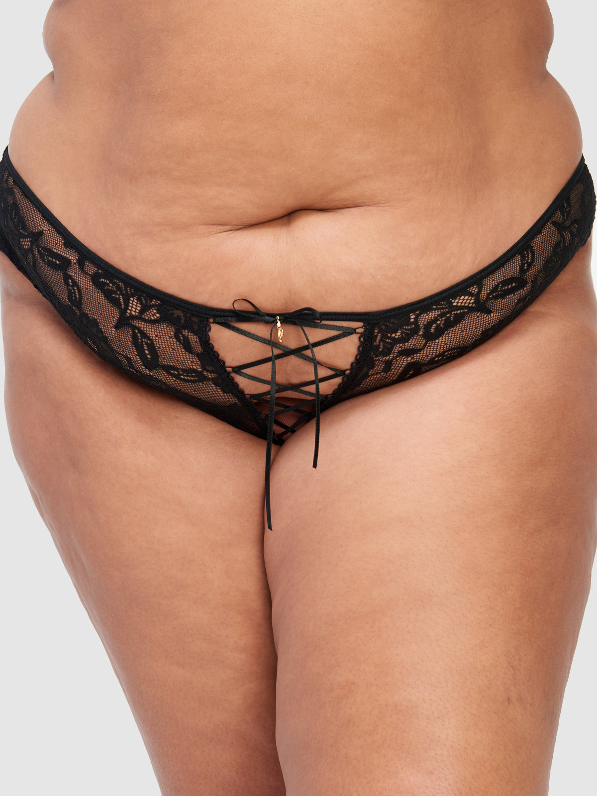 Model wears the Mabel Lace Up Front Tanga by Frederick's of Hollywood, featuring black stretch lace and crisscross lace-up detail at the front, shown waist to upper thighs against a plain background.