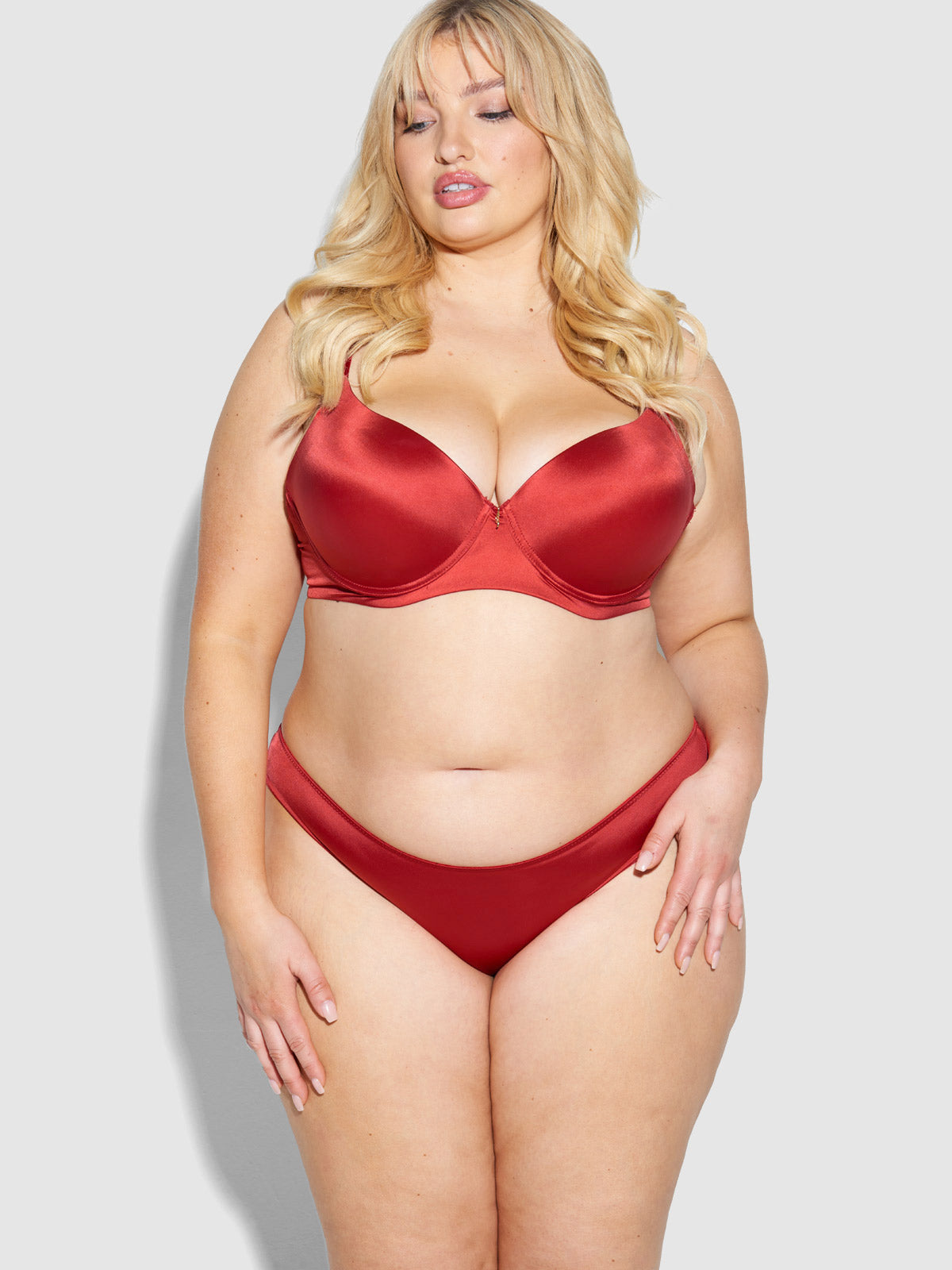 A woman with long blonde hair models the Frederick's of Hollywood Lexi Liquid Satin Hipster and matching bra set against a plain light gray background.